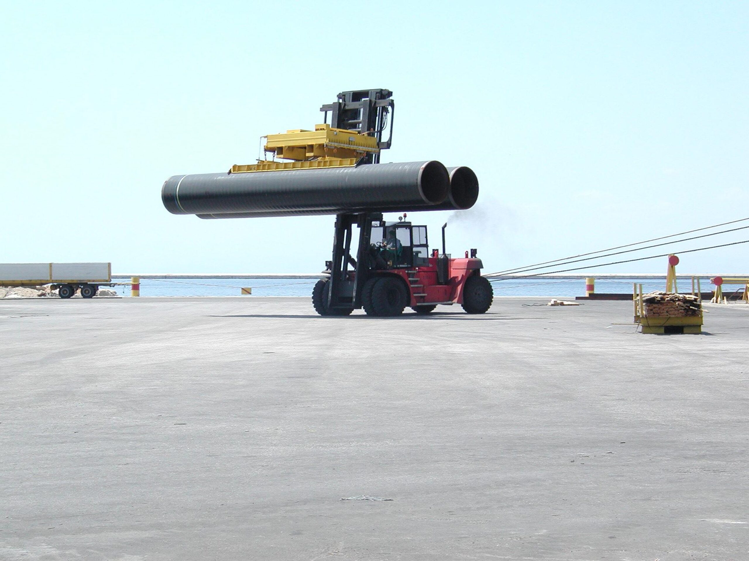 Palonnier de levage à vide pour tuyaux monté sur un chariot élévateur en pleine opération.