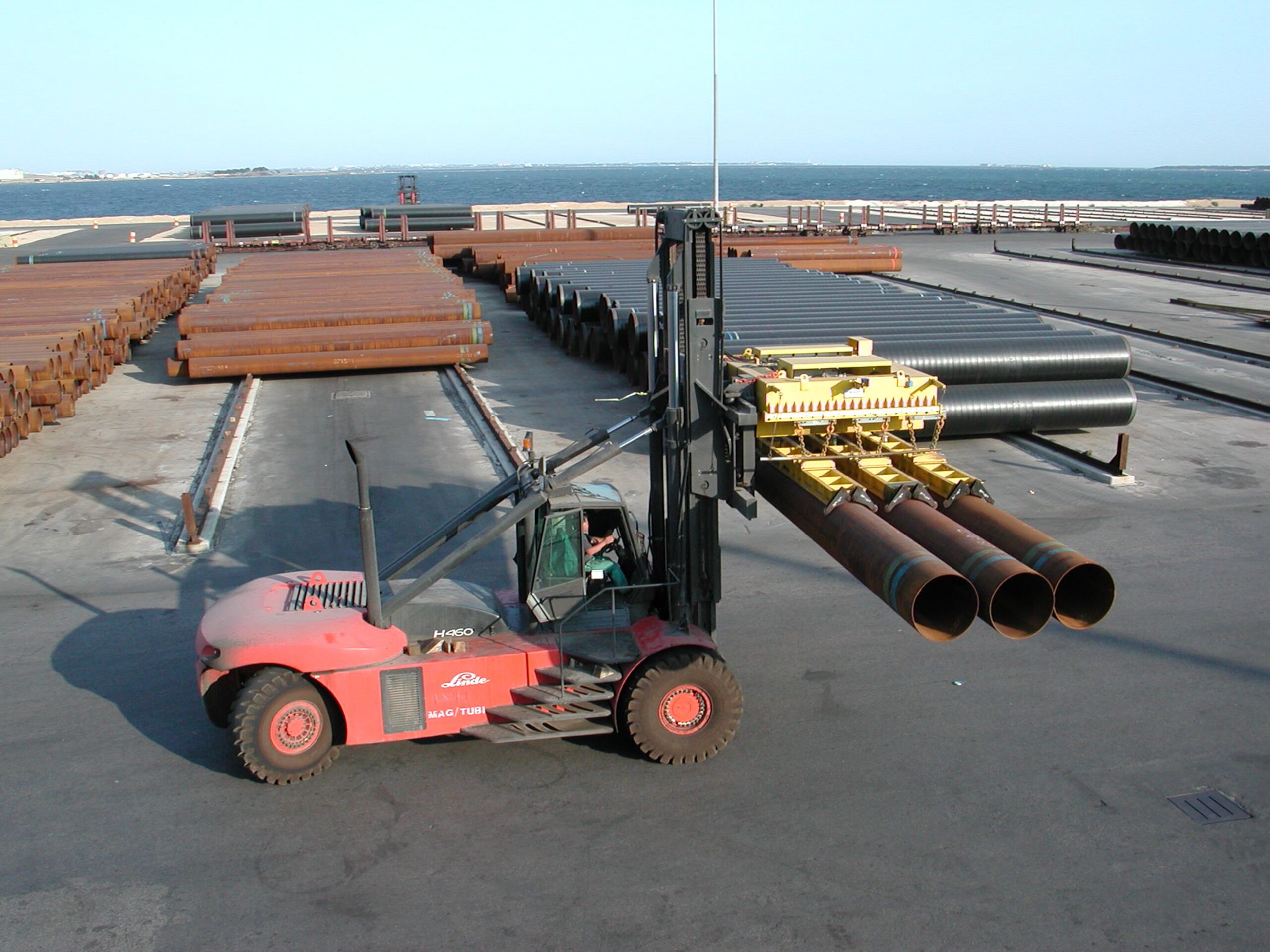 Vue latérale d’un palonnier de levage à vide pour tuyaux soulevant des tubes industriels.